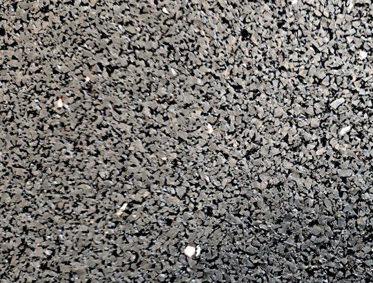 Superficie ravvicinata di gomma riciclata: granuli neri e grigi agglomerati con legante poliuretanico