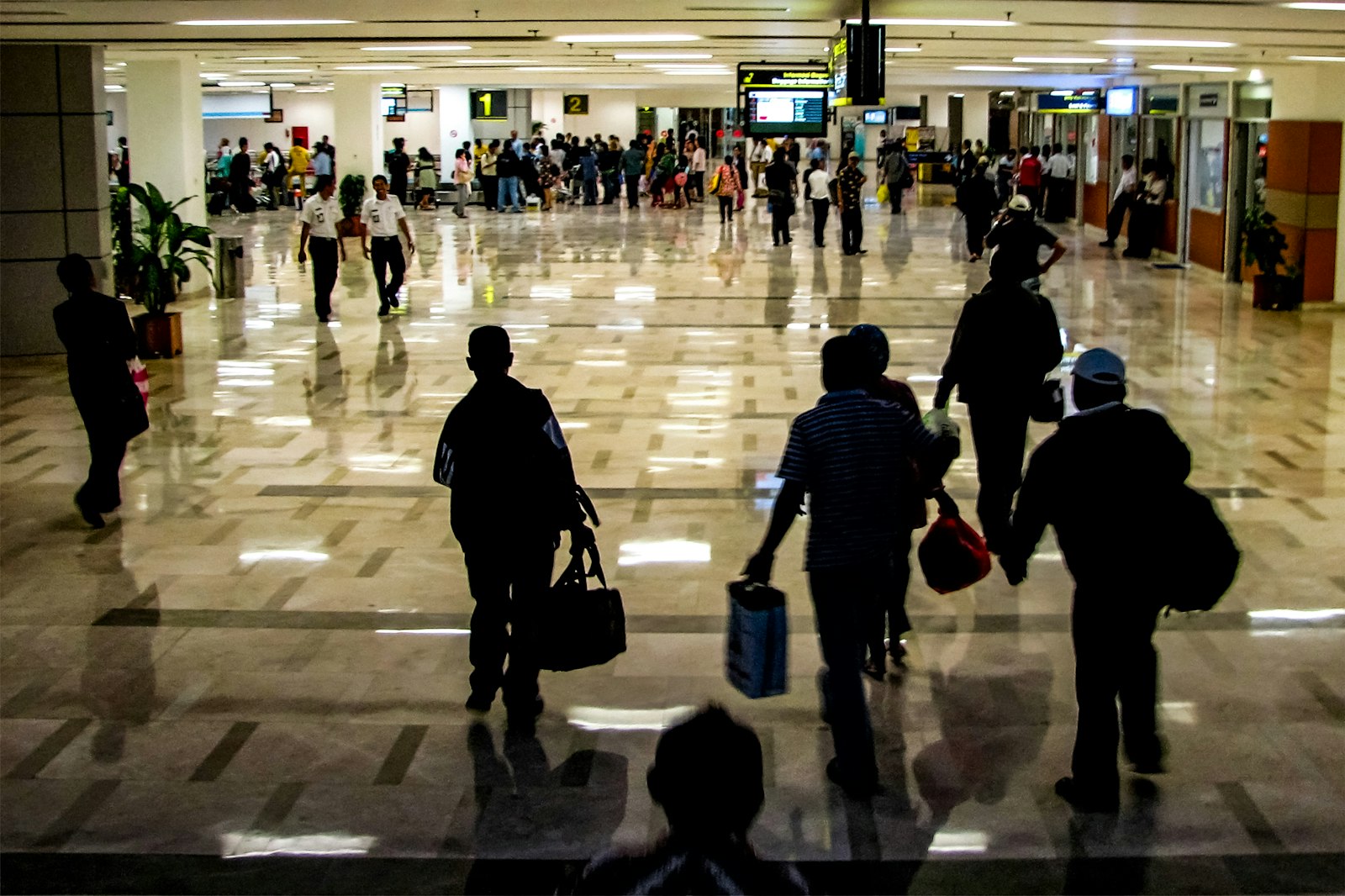 Persone in controluce che camminano sul pavimento lucido di un terminal