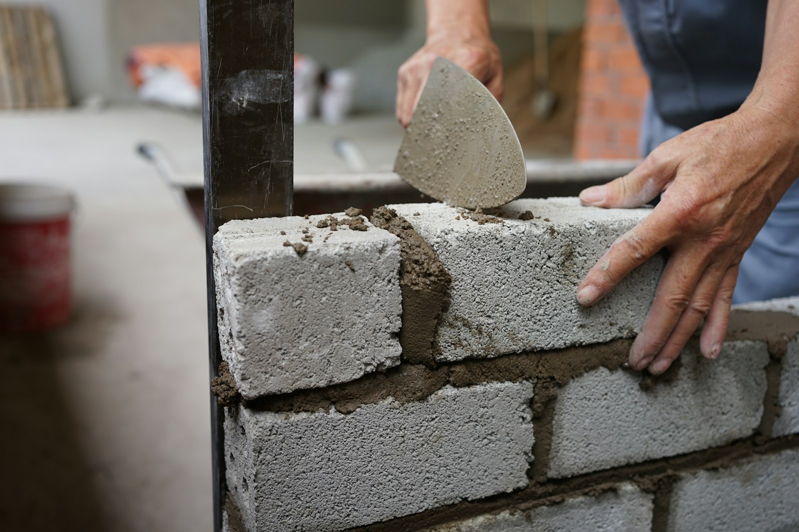 Muratore che posa blocchi in calcestruzzo con la cazzuola