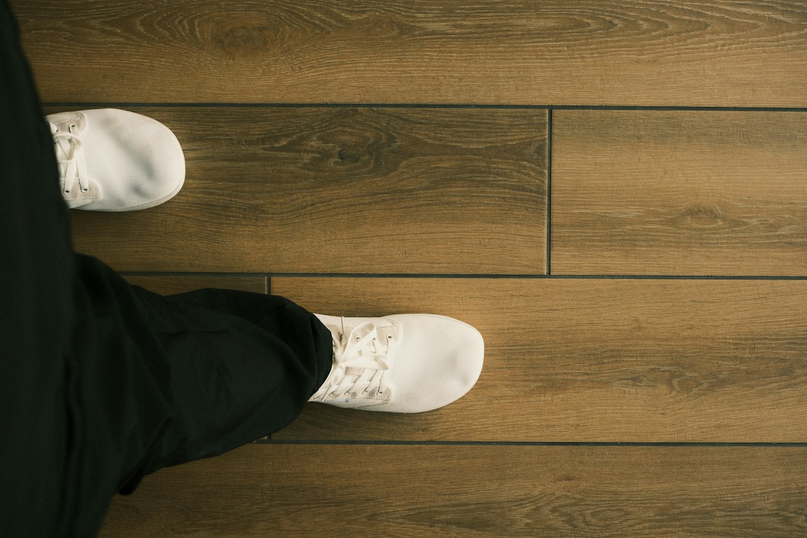 Passi con le scarpe da ginnastica su un pavimento in legno