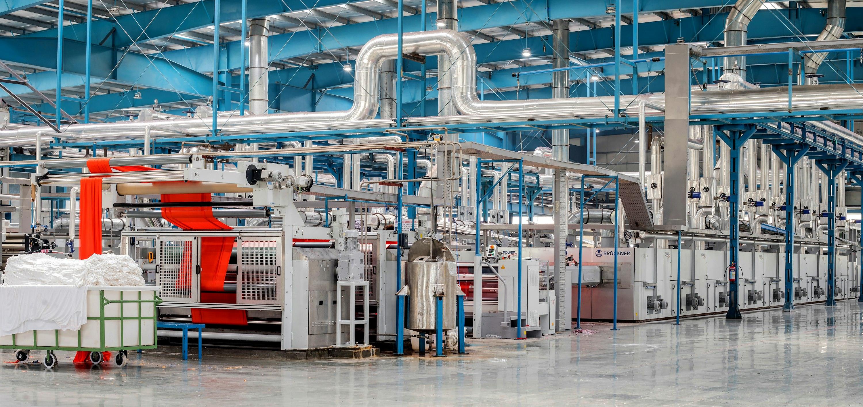 Reparto di finissaggio tessile con le macchine a terra e le tubazioni sospese