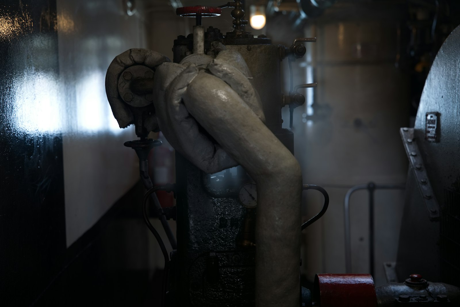 Sala macchine di una nave, con tubazioni e valvole in penombra