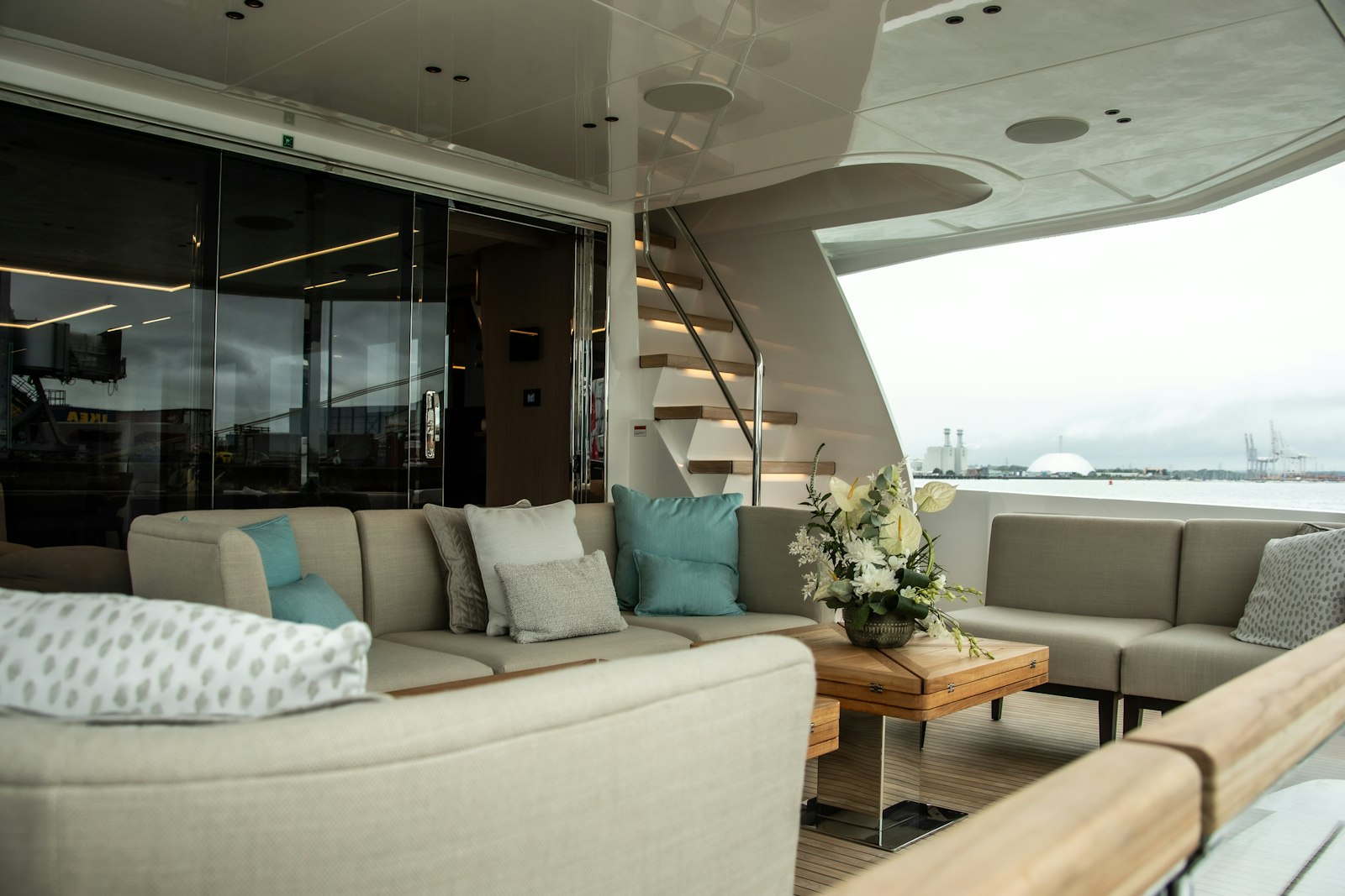 Salone di uno yacht con divani chiari e scala interna