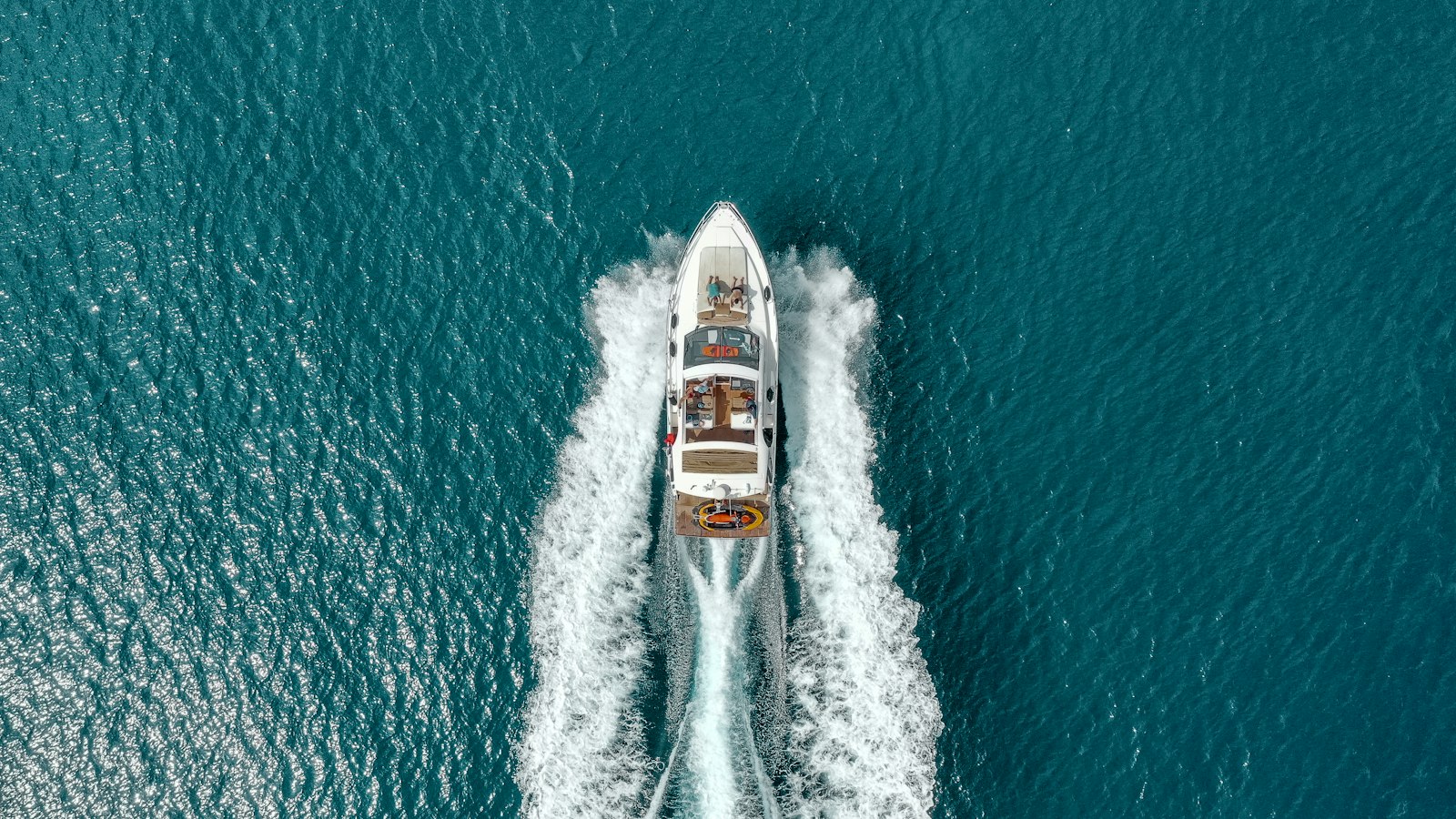 Yacht a motore in navigazione visto dall'alto, con la scia bianca sul mare